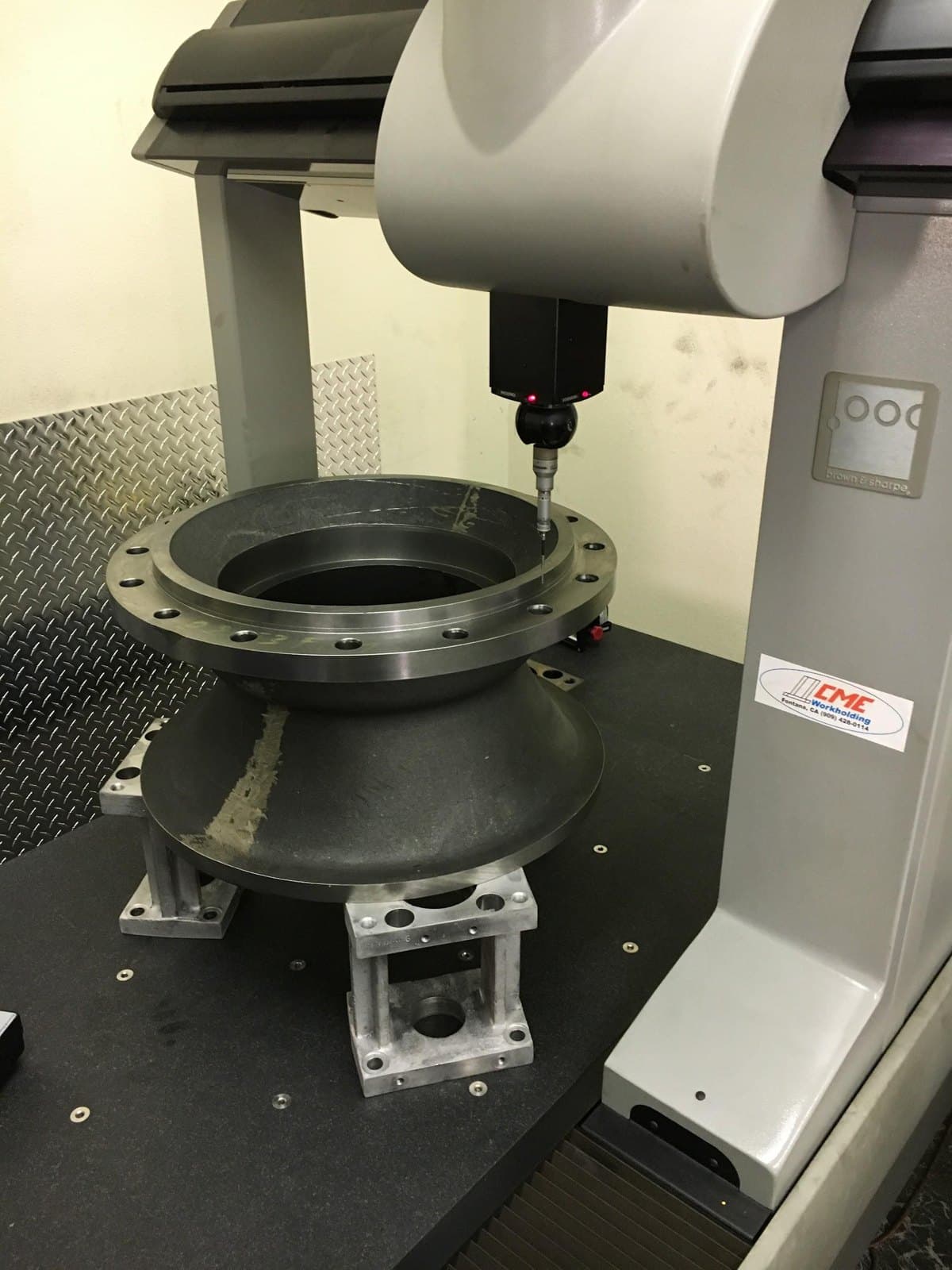 Fluid transfer pump casting staged under coordinate inspection equipment.