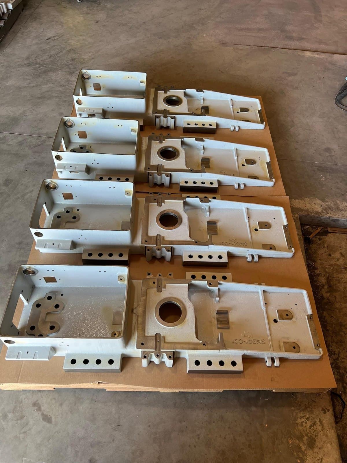 Railroad switch body castings arranged in rows on a shop table.